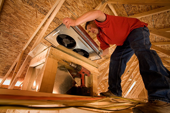 trabajador de la construcción instalando un ventilador en el ático